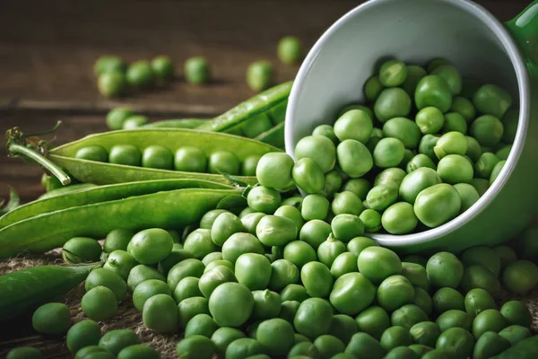 Délicieux pois verts mûrs couchés sur une table en bois. — Photo