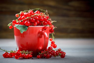 Ahşap bir masa üzerinde olgun kırmızı kuş üzümü.