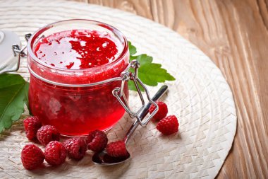 Ahşap bir masa üzerinde olgunlaşmış Ahududu ve Ahududu reçeli.