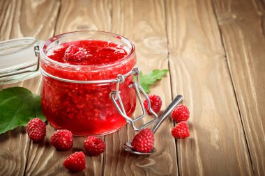 Ahşap bir masa üzerinde olgunlaşmış Ahududu ve Ahududu reçeli.