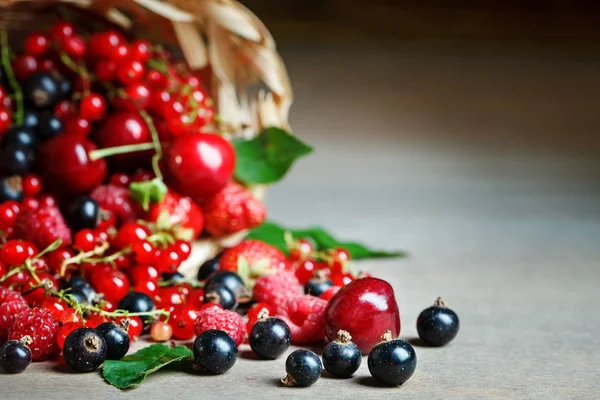 Ahşap bir masa üzerinde bir sepet içinde olgun çilek.