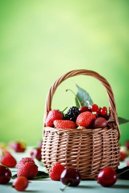 Ahşap bir masa üzerinde bir hasır sepet içinde olgun çilek.