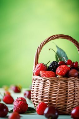 Ahşap bir masa üzerinde bir hasır sepet içinde olgun çilek.