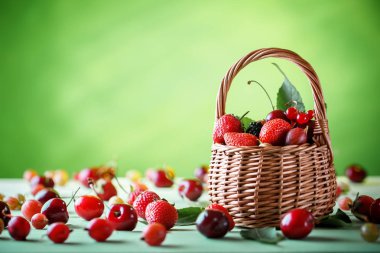 Ahşap bir masa üzerinde bir hasır sepet içinde olgun çilek.