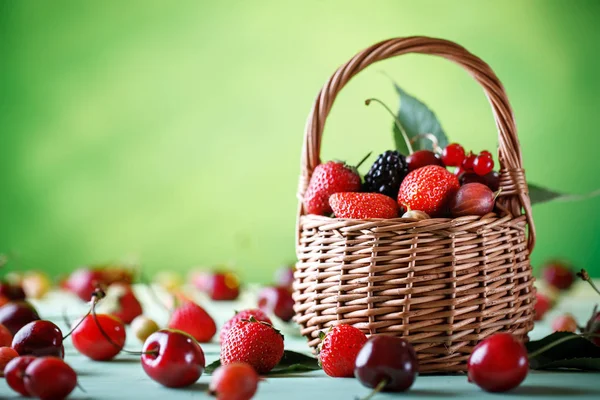 Ahşap bir masa üzerinde bir hasır sepet içinde olgun çilek.