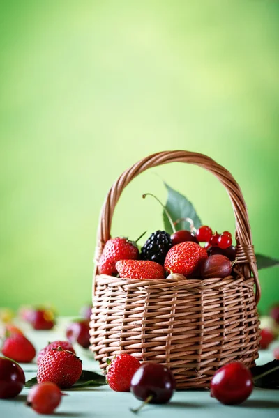 Ahşap bir masa üzerinde bir hasır sepet içinde olgun çilek.