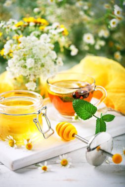 Çay, bir kavanoz bal ve çiçek sağlıklı bir fincan. Seçici odak.