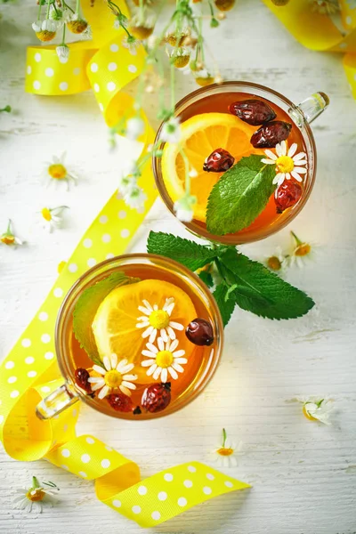 Eine gesunde Tasse Tee mit Zitrone, Hagebutte, Minze und Blumen. Selektiver Fokus. — Stockfoto