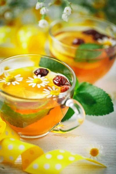 Eine gesunde Tasse Tee mit Zitrone, Hagebutte, Minze und Blumen. Selektiver Fokus. — Stockfoto