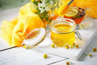 Çay, bir kavanoz bal ve çiçek sağlıklı bir fincan. Seçici odak.