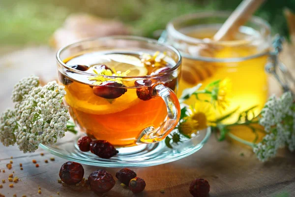 Köstlichen frischen Honig und eine Tasse gesunden Tee mit Zitrone und Hagebutten auf einem Holztisch. Selektiver Fokus. — Stockfoto