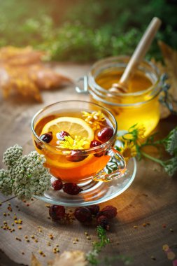 Lezzetli taze bal ve limon ve gül kalçalarına ahşap bir masa ile sağlıklı çay. Seçici odak.