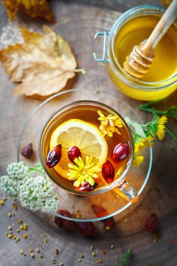 Lezzetli taze bal ve limon ve gül kalçalarına ahşap bir masa ile sağlıklı çay. Seçici odak.