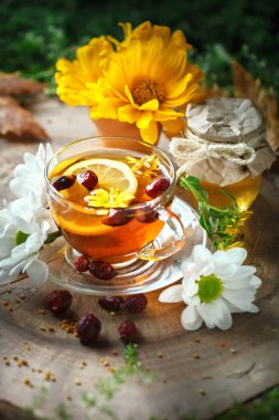 Lezzetli taze bal ve limon ve gül kalçalarına ahşap bir masa ile sağlıklı çay. Seçici odak.