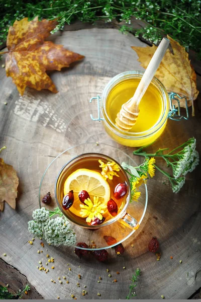 Delicioso mel fresco e uma xícara de chá saudável com limão e rosa quadris em uma mesa de madeira. Foco seletivo . — Fotografia de Stock