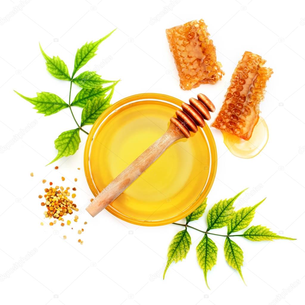 Jar of fresh honey, honeycomb and pollen on a white background.