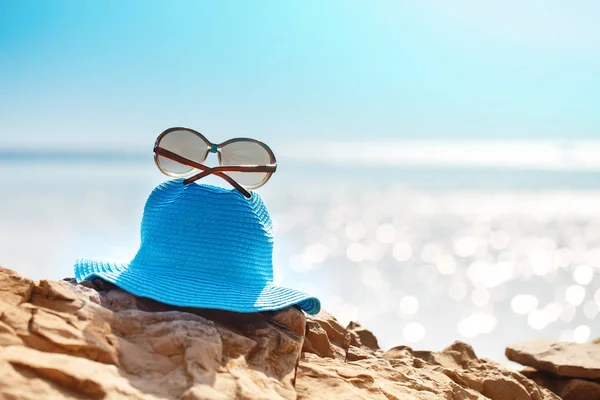 Sombrero y gafas de sol en la roca, mar despejado. Concepto de vacaciones de viaje . —  Fotos de Stock