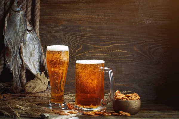 Vasos de cerveza y pescado seco sobre una mesa de madera . — Foto de Stock