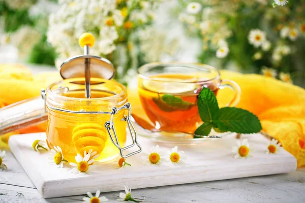 Çay, bir kavanoz bal ve çiçek sağlıklı bir fincan. Seçici odak.