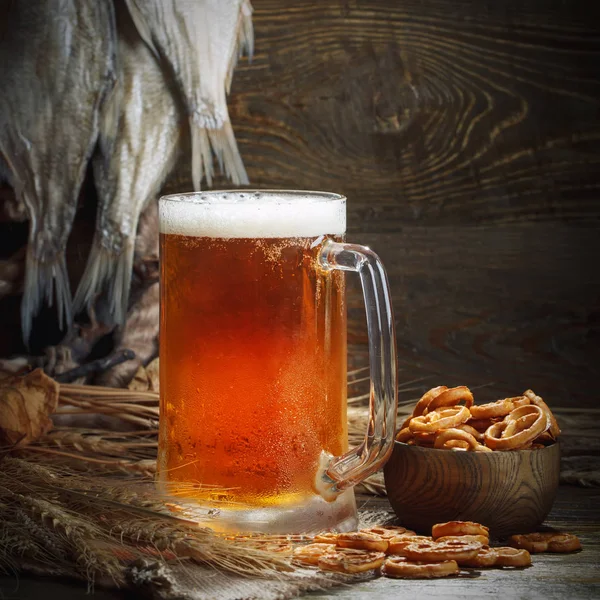 Bir bardak bira ve ahşap bir masa üzerinde kurutulmuş balık.