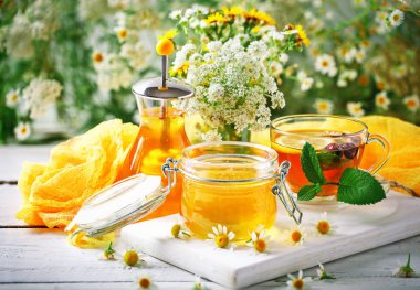 Çay, bir kavanoz bal ve çiçek sağlıklı bir fincan. Seçici odak.