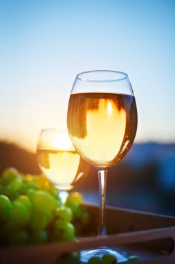 Gözlük günbatımı, evlerin yansıması ile beyaz şarap ile.