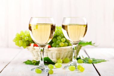 Gözlük beyaz şarap ve ahşap bir masa üzerinde taze üzüm ile.