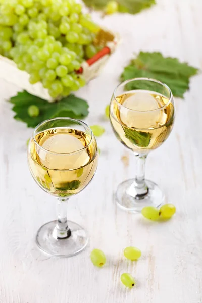 Verres avec vin blanc et raisins frais sur une table en bois . — Photo