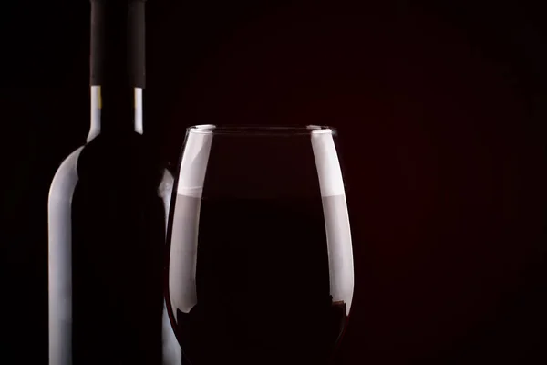 Bottiglia di vino rosso e un bicchiere di vino rosso su sfondo scuro . — Foto Stock
