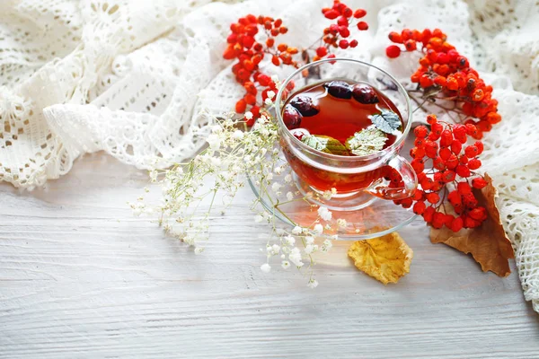 Eine Tasse Tee und Vogelbeeren auf einem Holztisch. Herbst-Stillleben. — Stockfoto