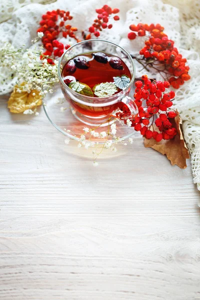 Bir fincan çay ve üvez meyveleri ahşap bir masa üzerinde. Sonbahar natürmort.