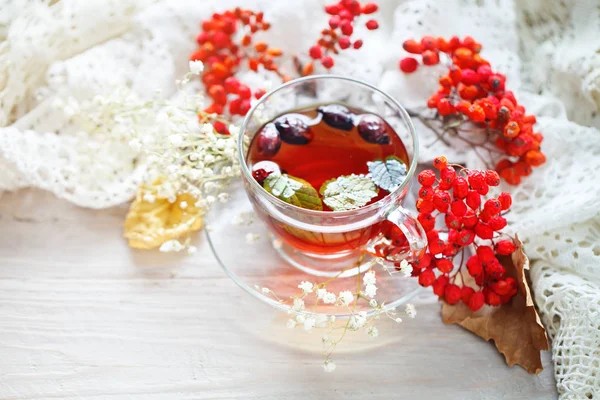 Eine Tasse Tee und Vogelbeeren auf einem Holztisch. Herbst-Stillleben. — Stockfoto