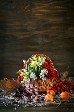 Ahşap masa kır çiçekleri, üvez meyveleri ve sonbahar yaprakları ile süslenmiş.
