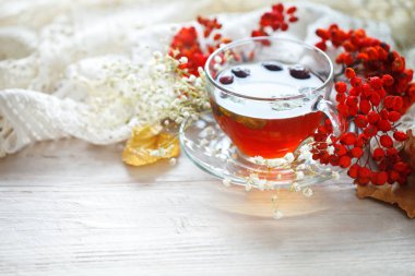 Bir fincan çay ve üvez meyveleri ahşap bir masa üzerinde. Sonbahar natürmort.