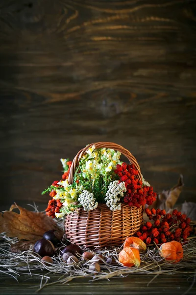 Ahşap masa kır çiçekleri, üvez meyveleri ve sonbahar yaprakları ile süslenmiş.