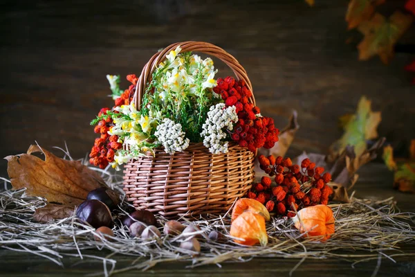 Ahşap masa kır çiçekleri, üvez meyveleri ve sonbahar yaprakları ile süslenmiş.
