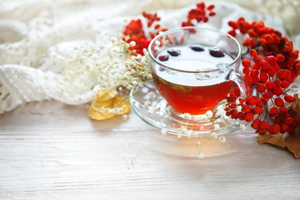 Bir fincan çay ve üvez meyveleri ahşap bir masa üzerinde. Sonbahar natürmort.