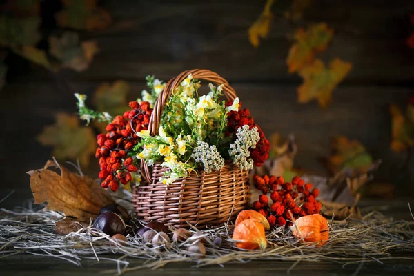 Ξύλινο τραπέζι διακοσμημένο με λουλούδια, Rowan μούρα και φθινοπωρινά φύλλα. — Φωτογραφία Αρχείου