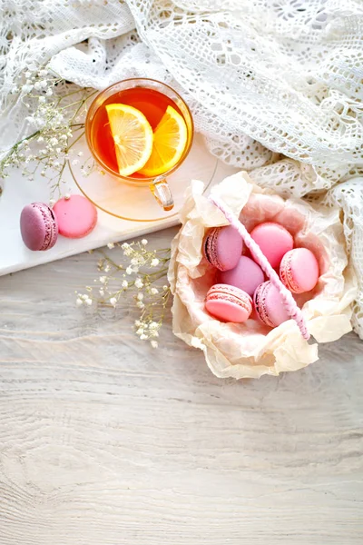 Çay limon, kır çiçekleri ve beyaz tahta masada macaron.