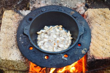 Adam açık havada bir kazan içinde ulusal pilav aşçılar.