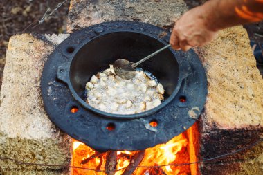 Adam açık havada bir kazan içinde ulusal pilav aşçılar.