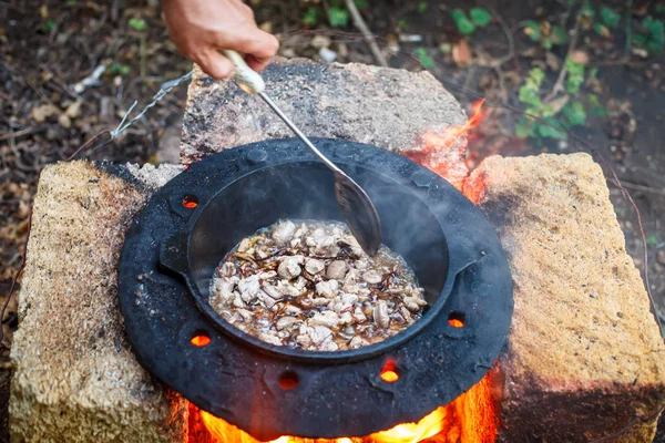 The man cooks national pilaf in a cauldron outdoors. — Stock Photo, Image