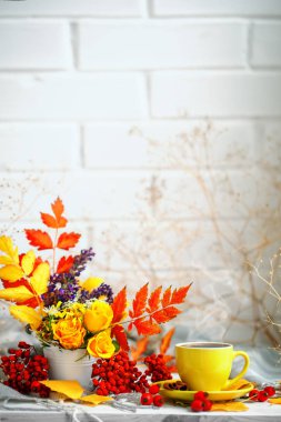 Bir fincan kahve, sonbahar yaprakları ve ahşap bir masaya çiçek. Sonbahar natürmort. Seçici odak.