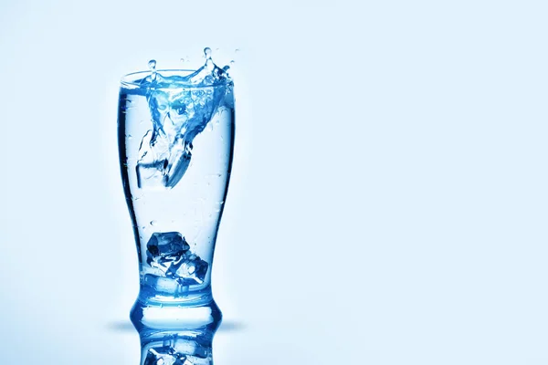 Kostki lodu, pokrywające się w szklance wody. Odrobiny wody, podłoże z miejsca kopii. — Zdjęcie stockowe
