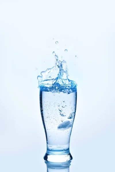 The ice cubes lapping in water glass. Water splashes, Background with copy space.