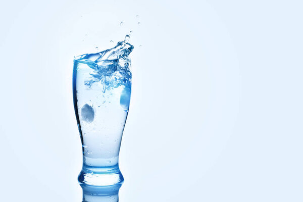 Ледяные кубики, кружащиеся в стакане. Брызги воды, фон с копировальным пространством
.