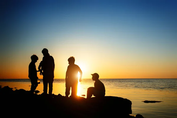Children on the beach, fishing. Sunset shot, rear view. Sea background. — Stock Photo, Image