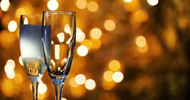 Champagner wird vor dem Hintergrund der Neujahrsgirlanden in Gläser gegossen. — Stockvideo