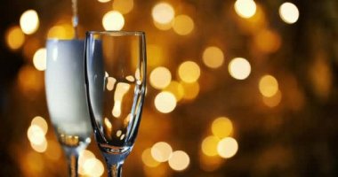 Şampanya kadehlere doldurulur Yeni Yıl çelengi arkaplanına karşı.