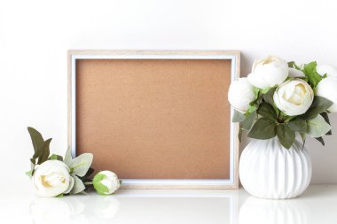 Frame mock up and plants in a vase on on the table. White colors. Greeting card. Background with copy space.